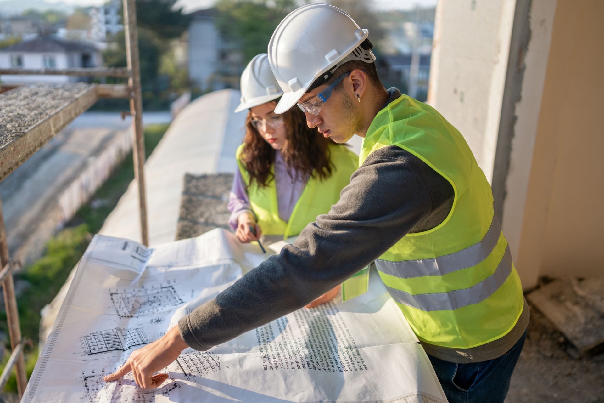 A man and a woman are looking at a blueprint on a construction site.