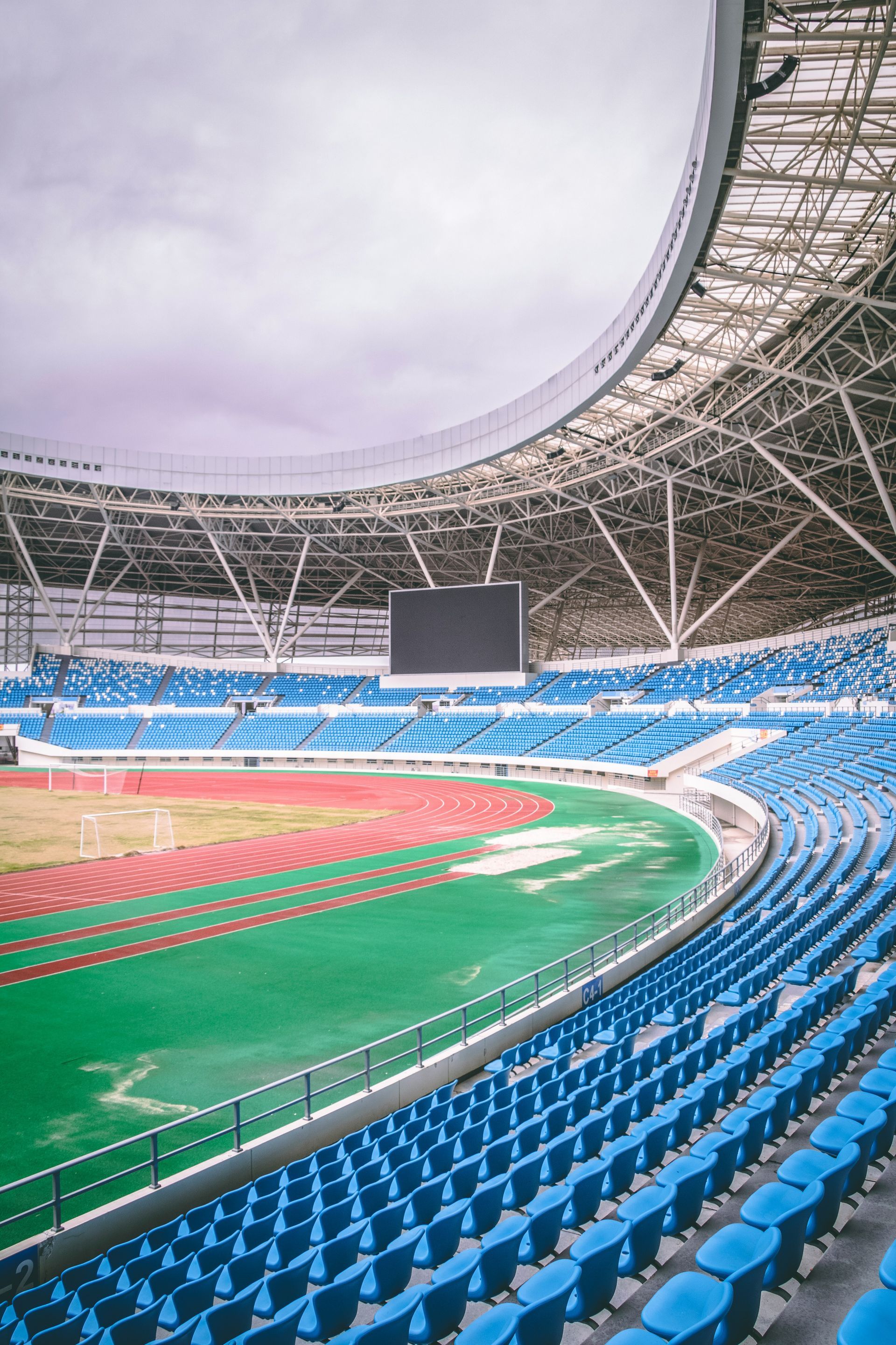 An empty stadium with blue seats and a green field.