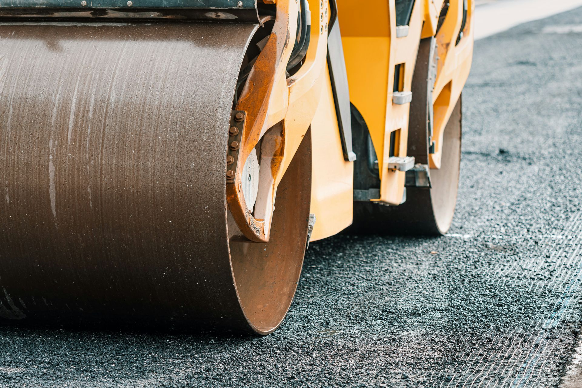 A yellow roller is rolling asphalt on a road.