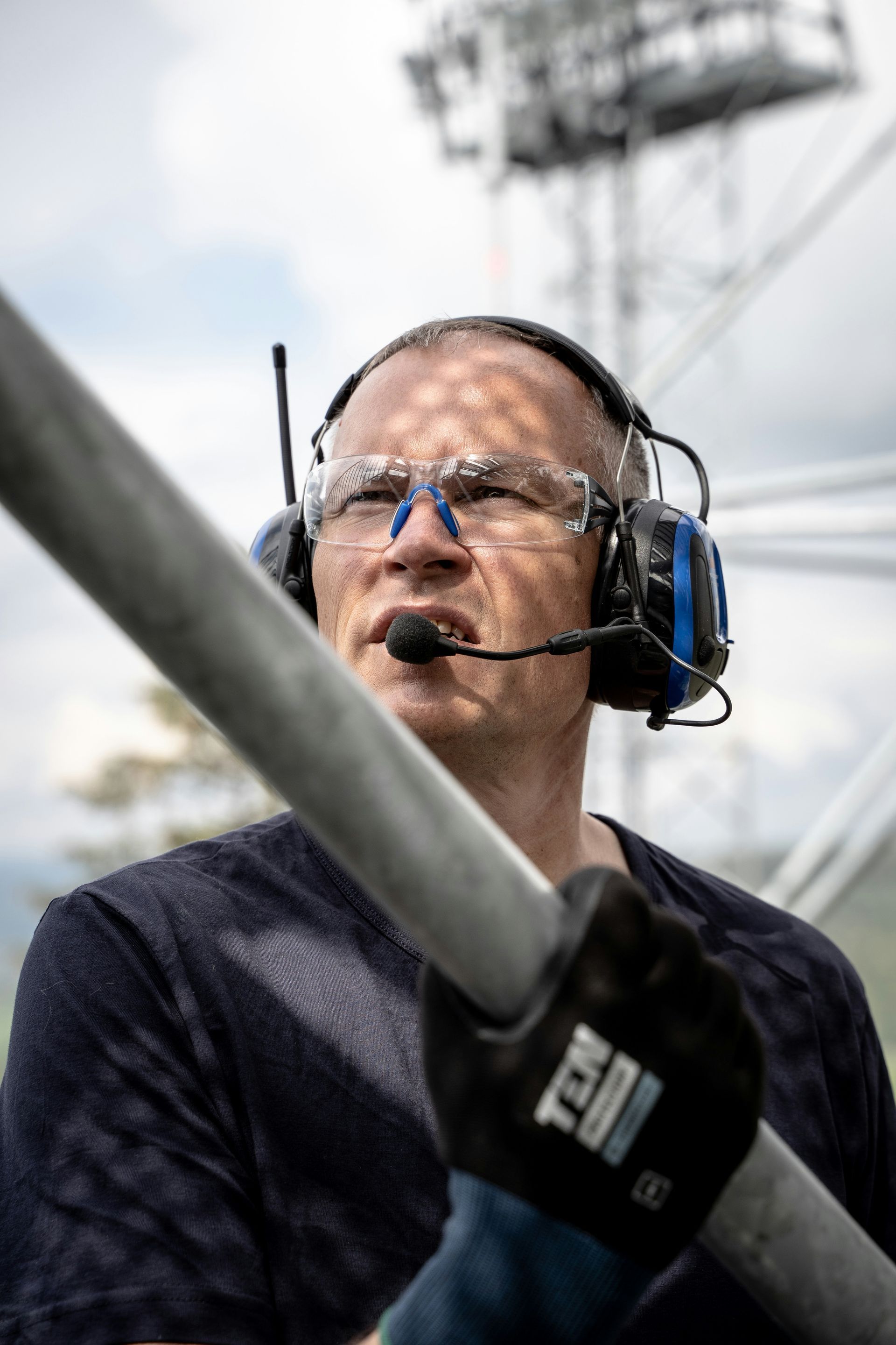 A man wearing headphones and glasses is holding a metal pole.