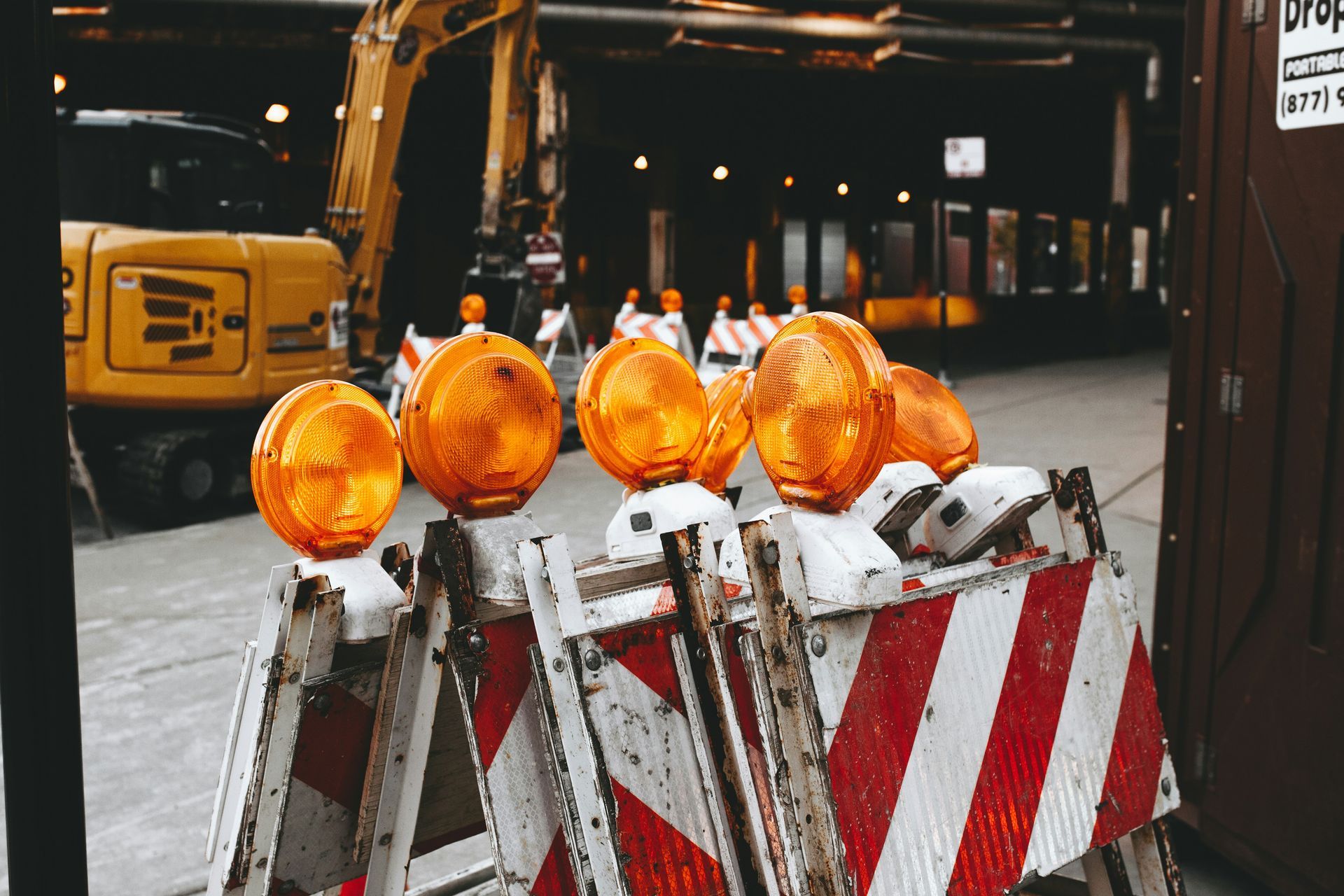 A red and white construction barrier with orange lights on top of it.