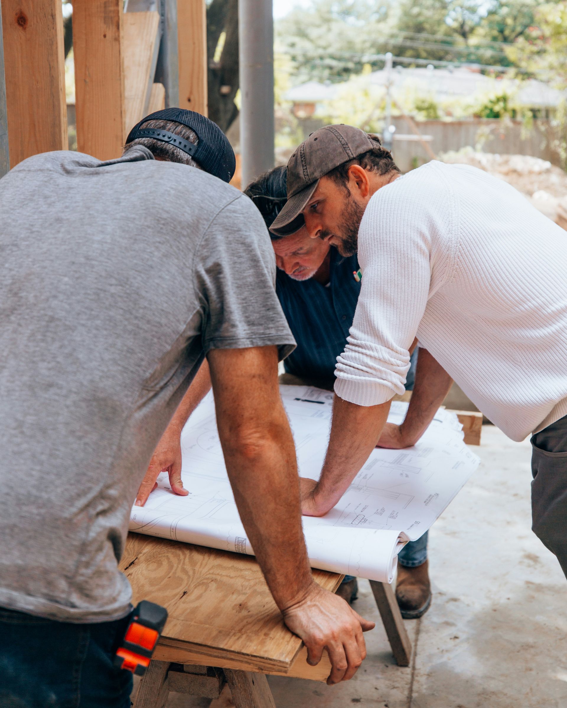 Two men are looking at a blueprint on a table.