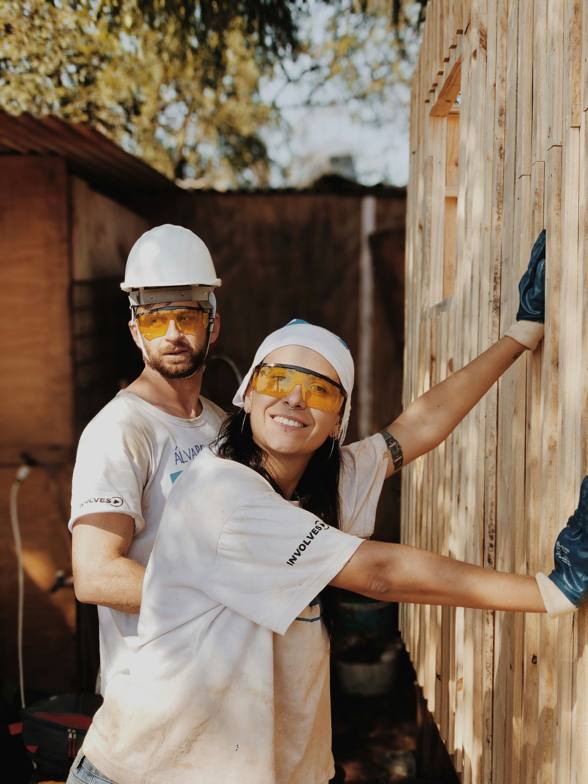 A man and a woman are working on a wooden wall.