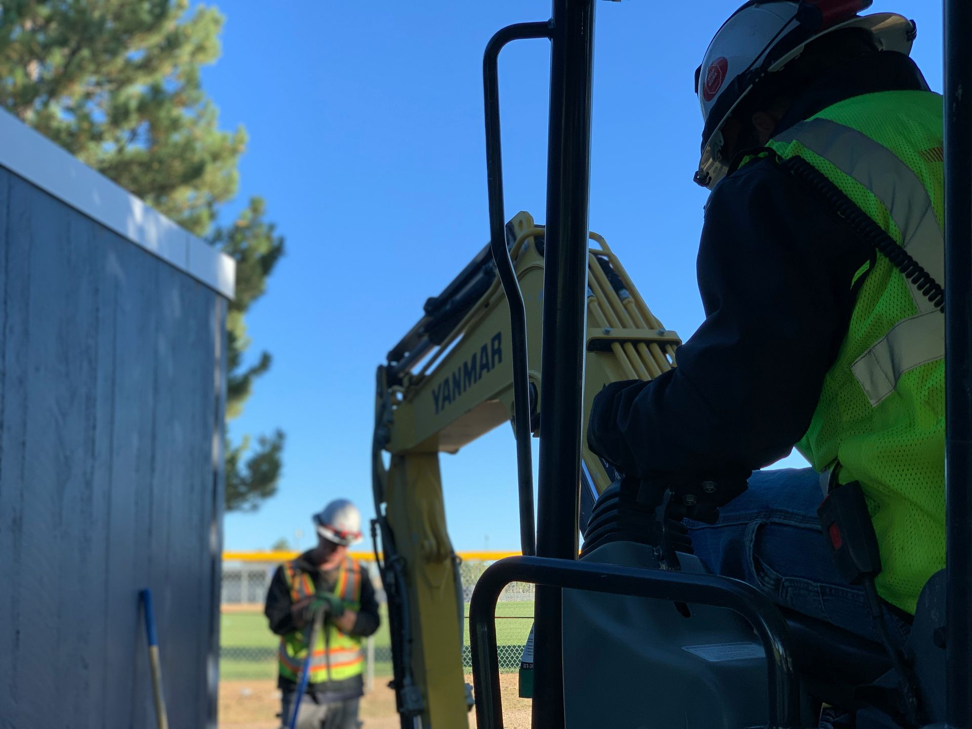 A construction worker is driving an excavator on a construction site.