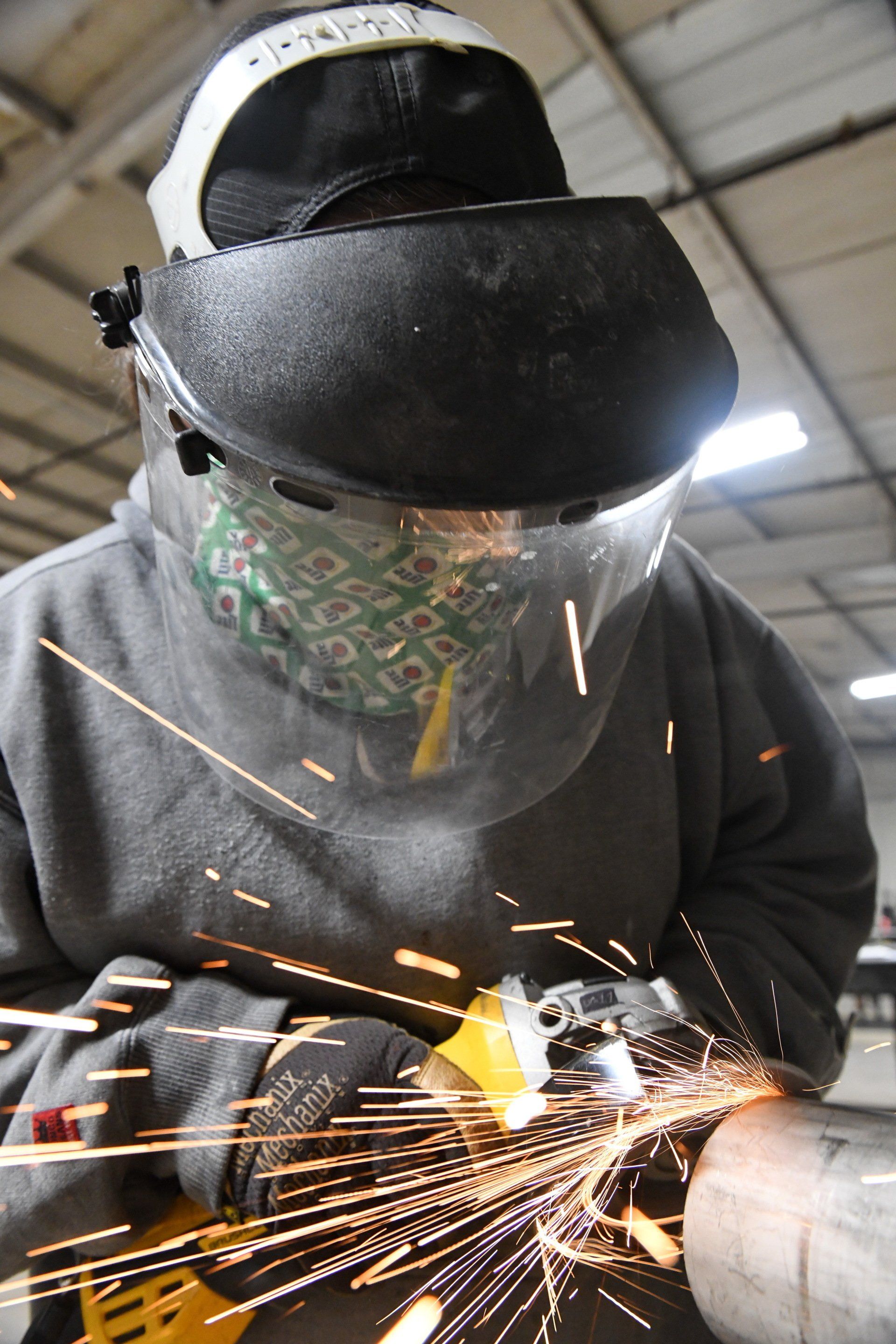 Apprentice grinding the outside of a pipe to provide  shiny finish to the steel