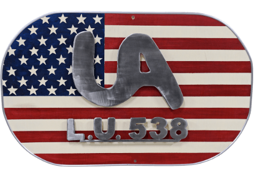 custom steel art created by apprentices at Local 538. Oval shaped with USA flag background and text in shiny steel reading UA L.U. 538