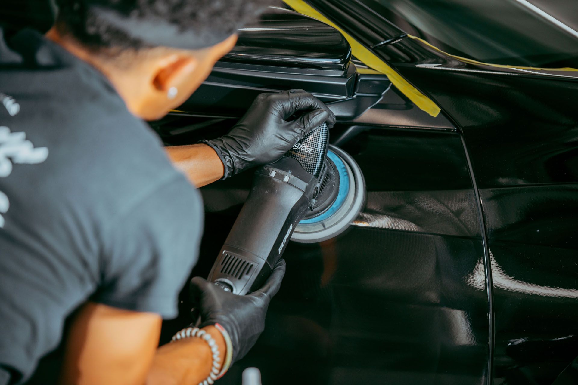 A man is polishing a black car with a machine.