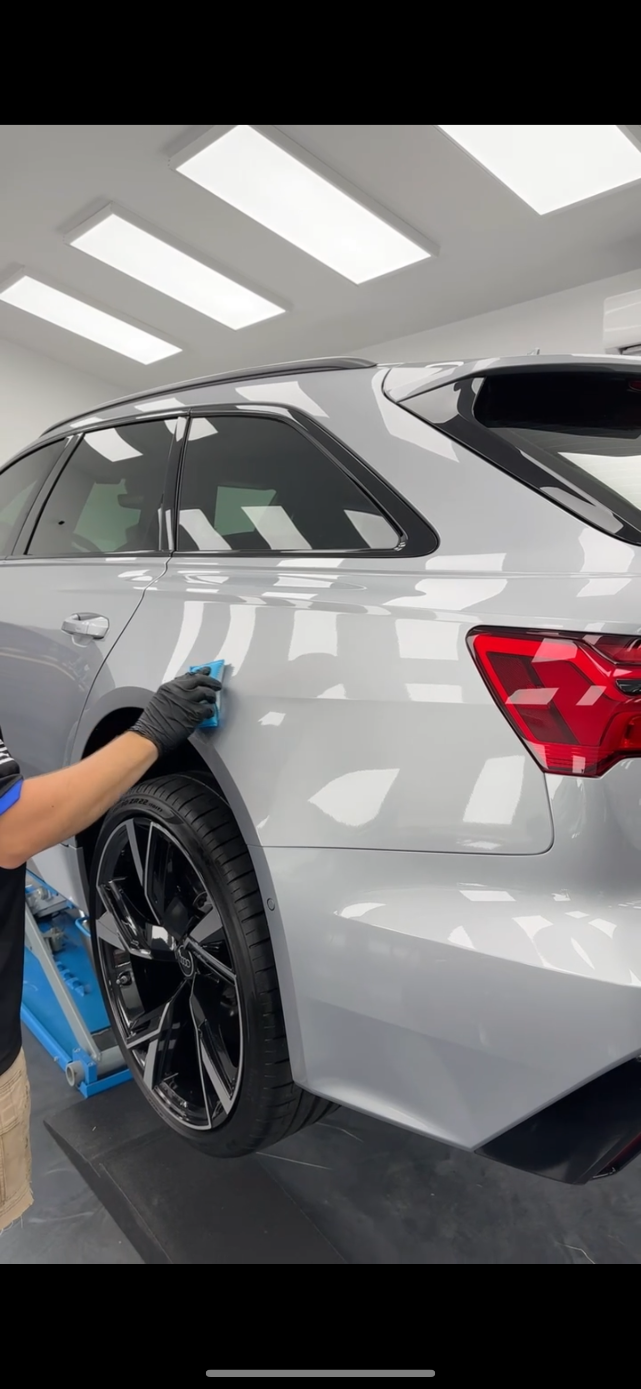 A person is polishing the hood of a red car.