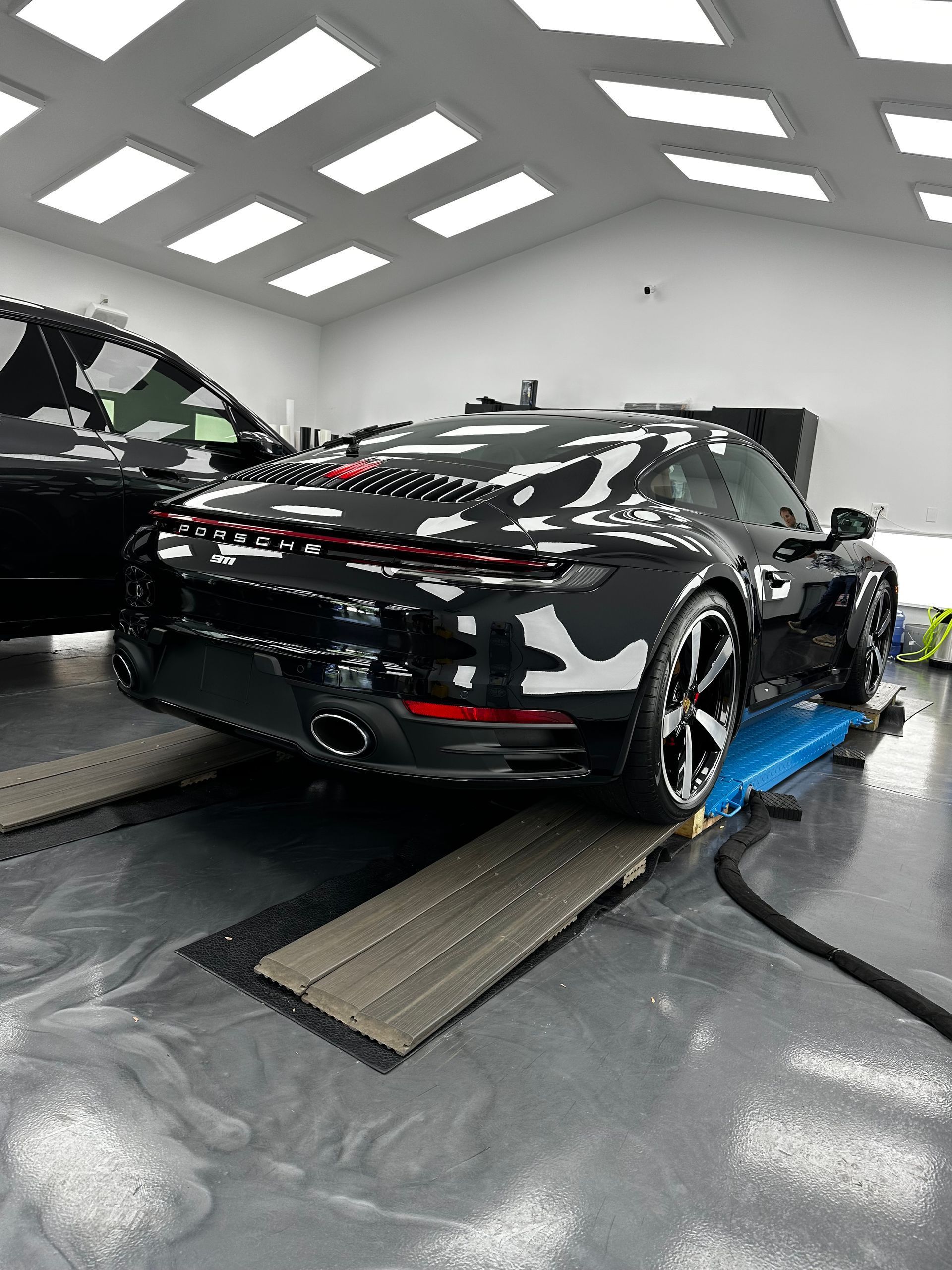 A man is applying a protective film to the headlights of a mercedes benz.