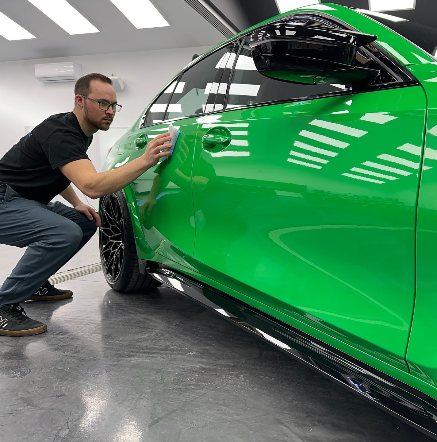A person is polishing a red car in a garage.