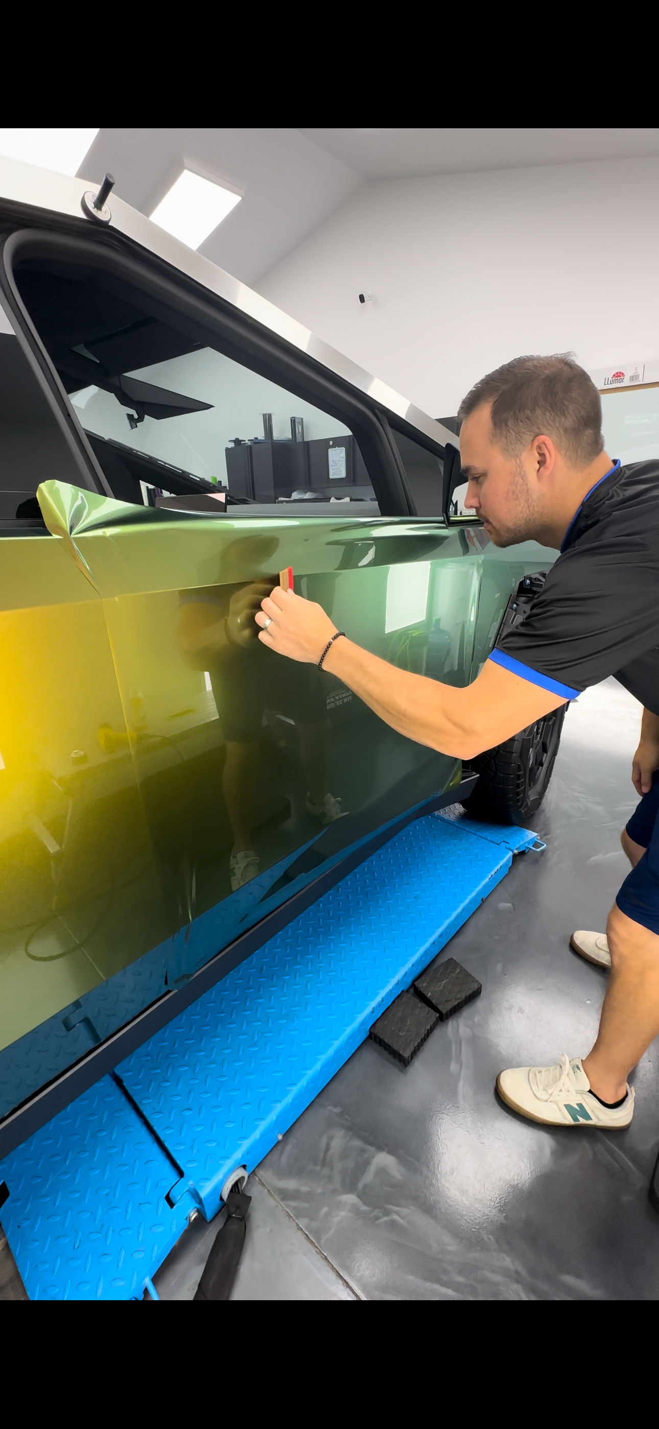 A man is wrapping a blue car with a blue wrap.