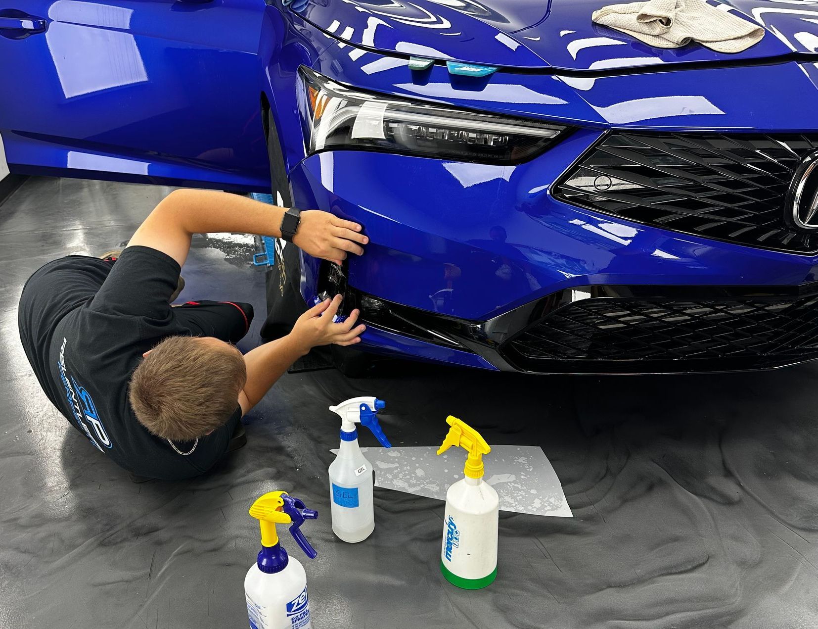 A man is polishing the headlight of a white car.