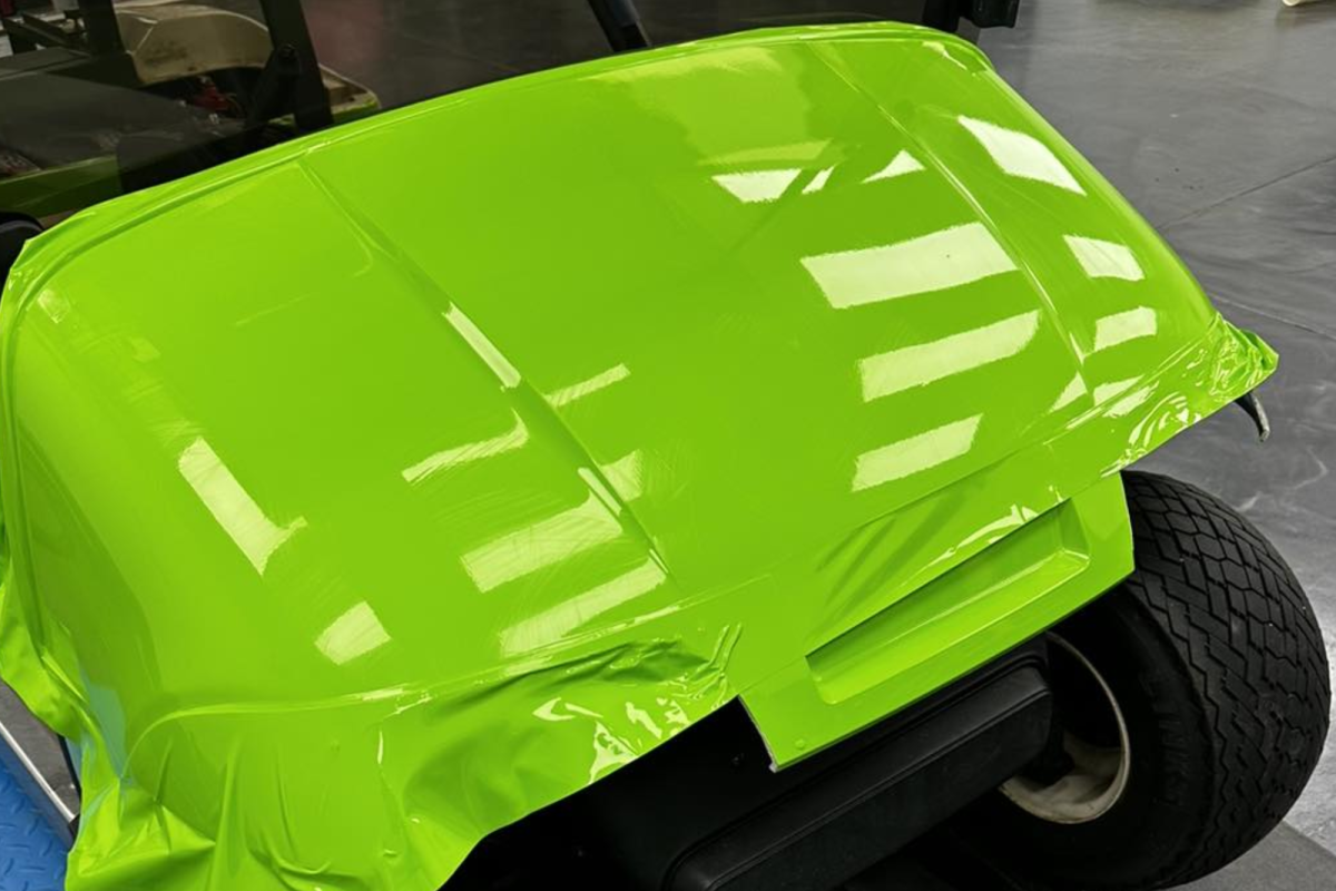 A green golf cart is wrapped in green tape.