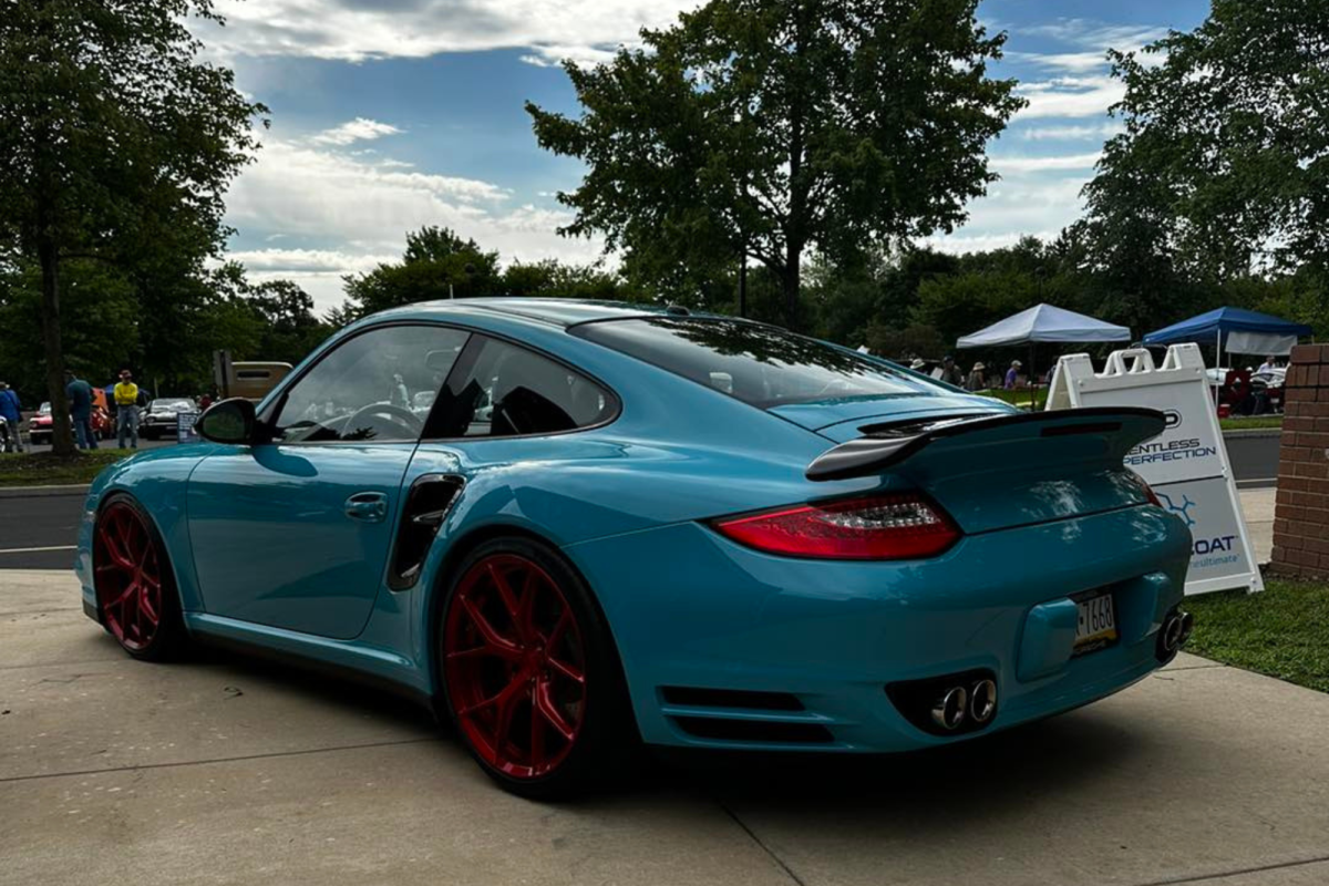 A blue porsche turbo is parked on the side of the road.