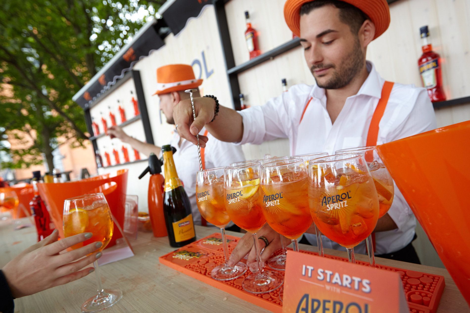 a man in an orange hat is pouring a drink into a glass .