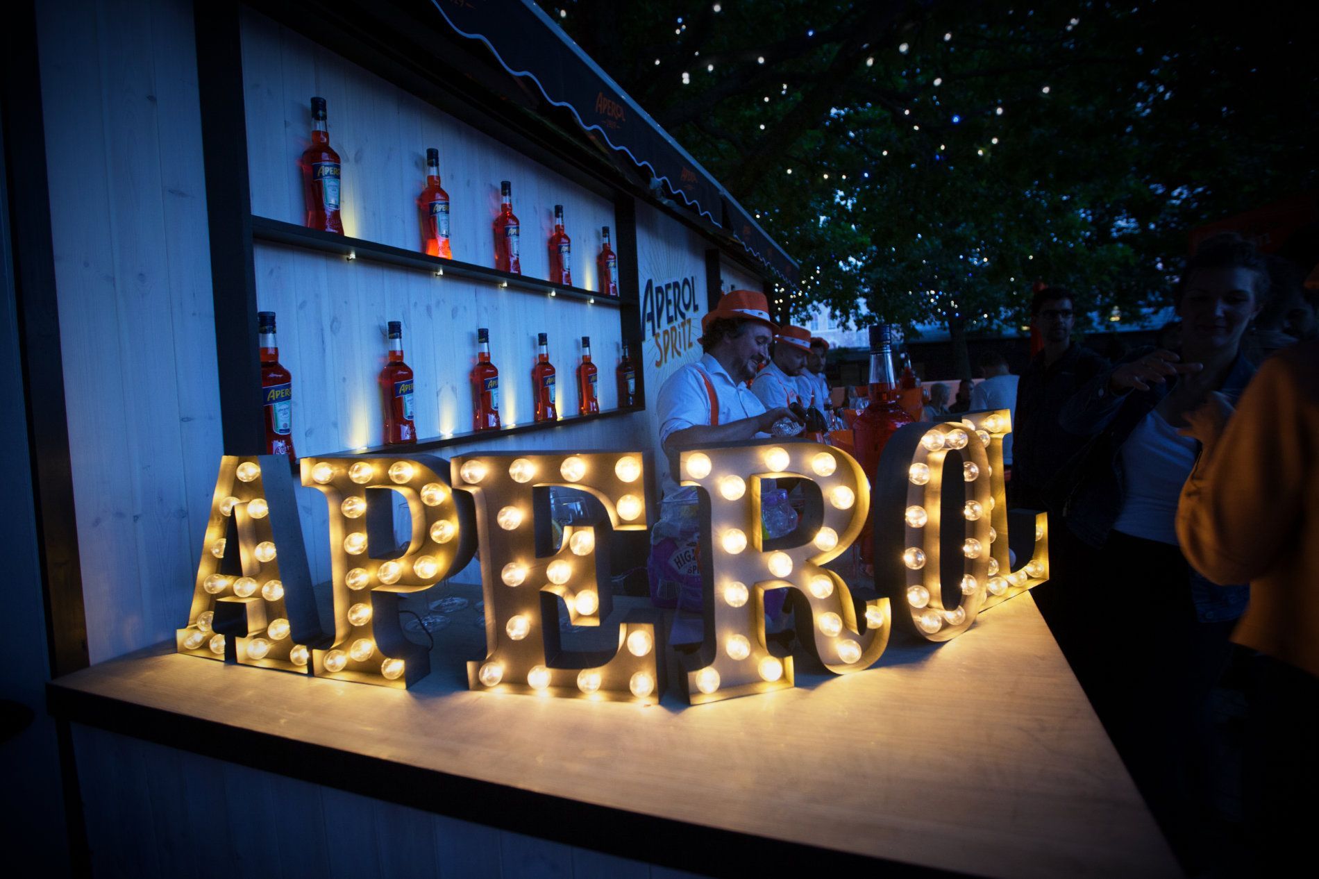 a sign that says aperol is lit up at night
