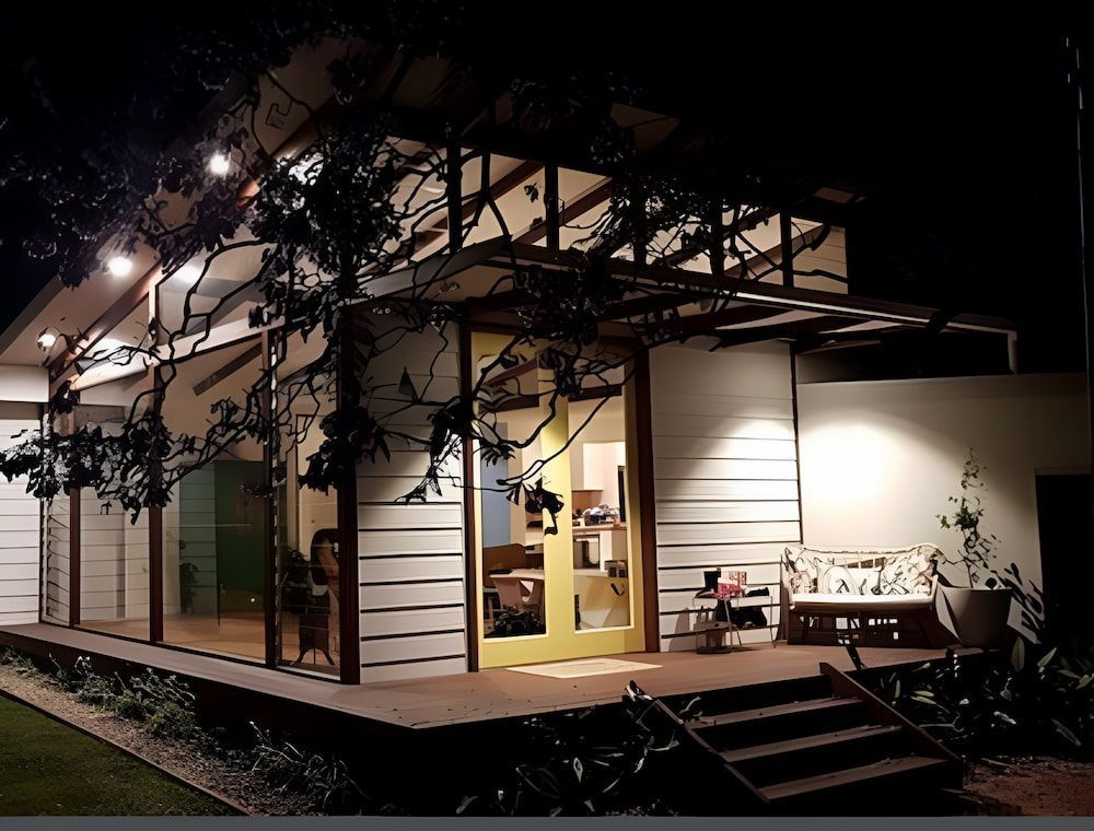 A House With A Porch And Stairs Is Lit Up At Night — Matt Loder Constructions in Bulli, NSW