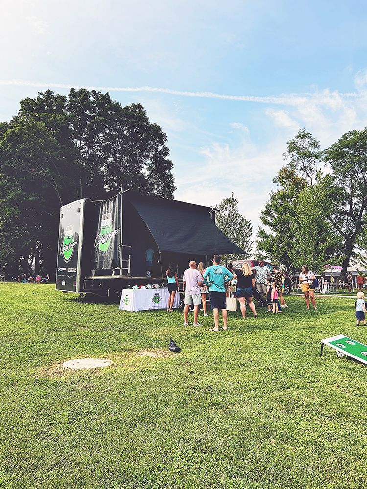 A group of people are standing in a grassy field in front of a stage.