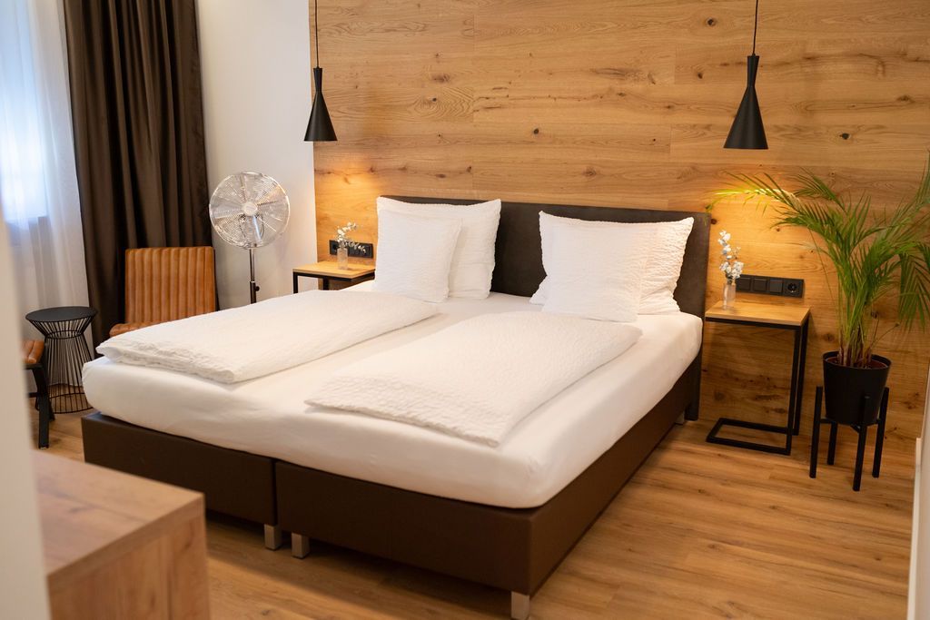 Eiche Queensize. Bett an holzverkleideten Wand. Warme Beleuchtung