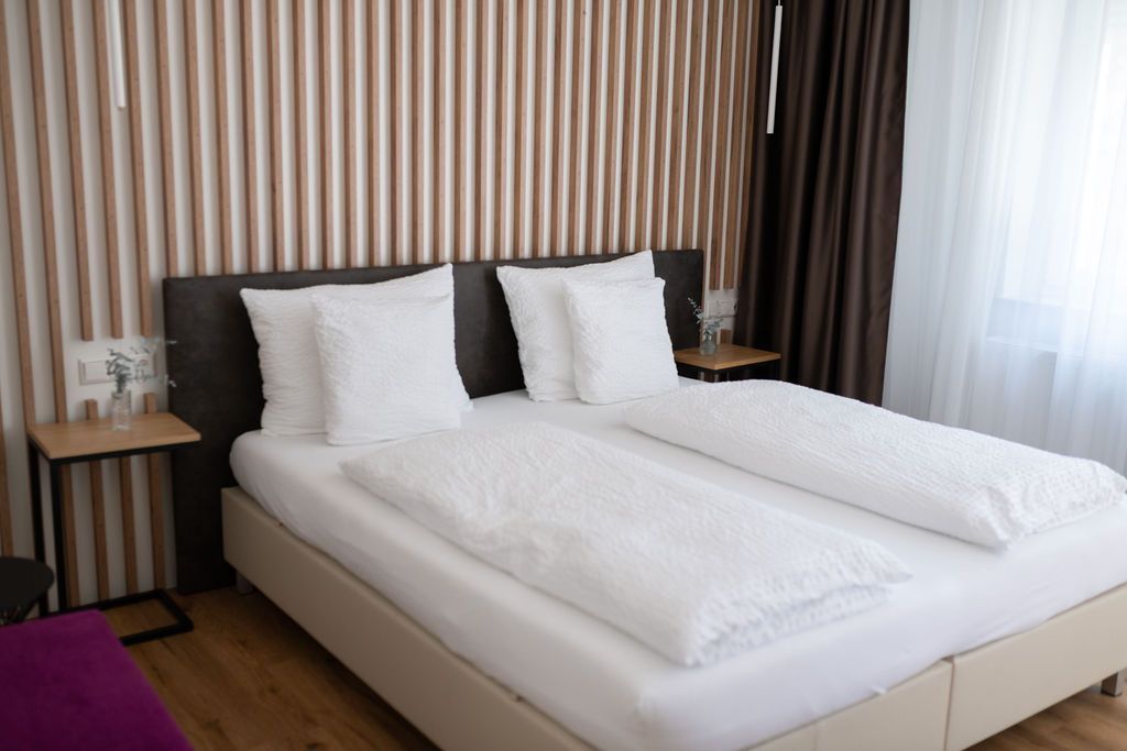 Garten Zimmer. Großes Doppelbett. Die Wand hinter dem Bett ist mit Eiche-Holzpanelen verkleidet. Viel natürliches Licht.