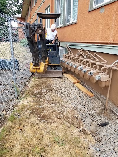 A man is driving a small bulldozer in front of a building.