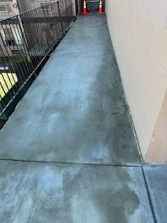 A concrete walkway leading to a building with stairs.