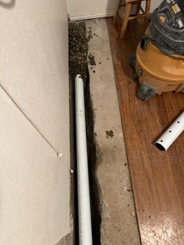 A vacuum cleaner is sitting on the floor next to a white pipe.