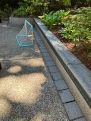 A soccer net is sitting on the sidewalk next to a brick wall.