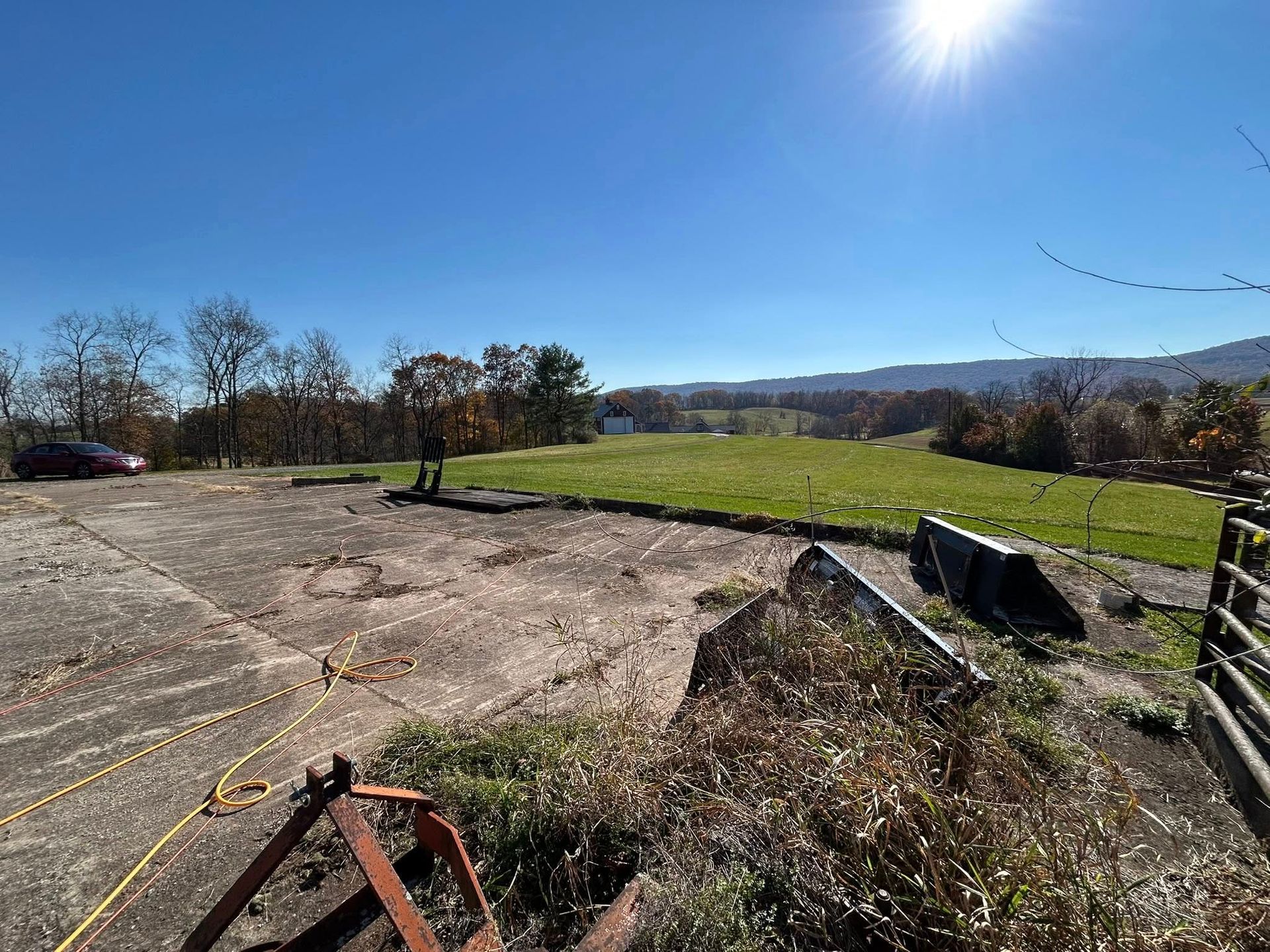 Woman in straw hat smiles, holding wine glass near a lake.