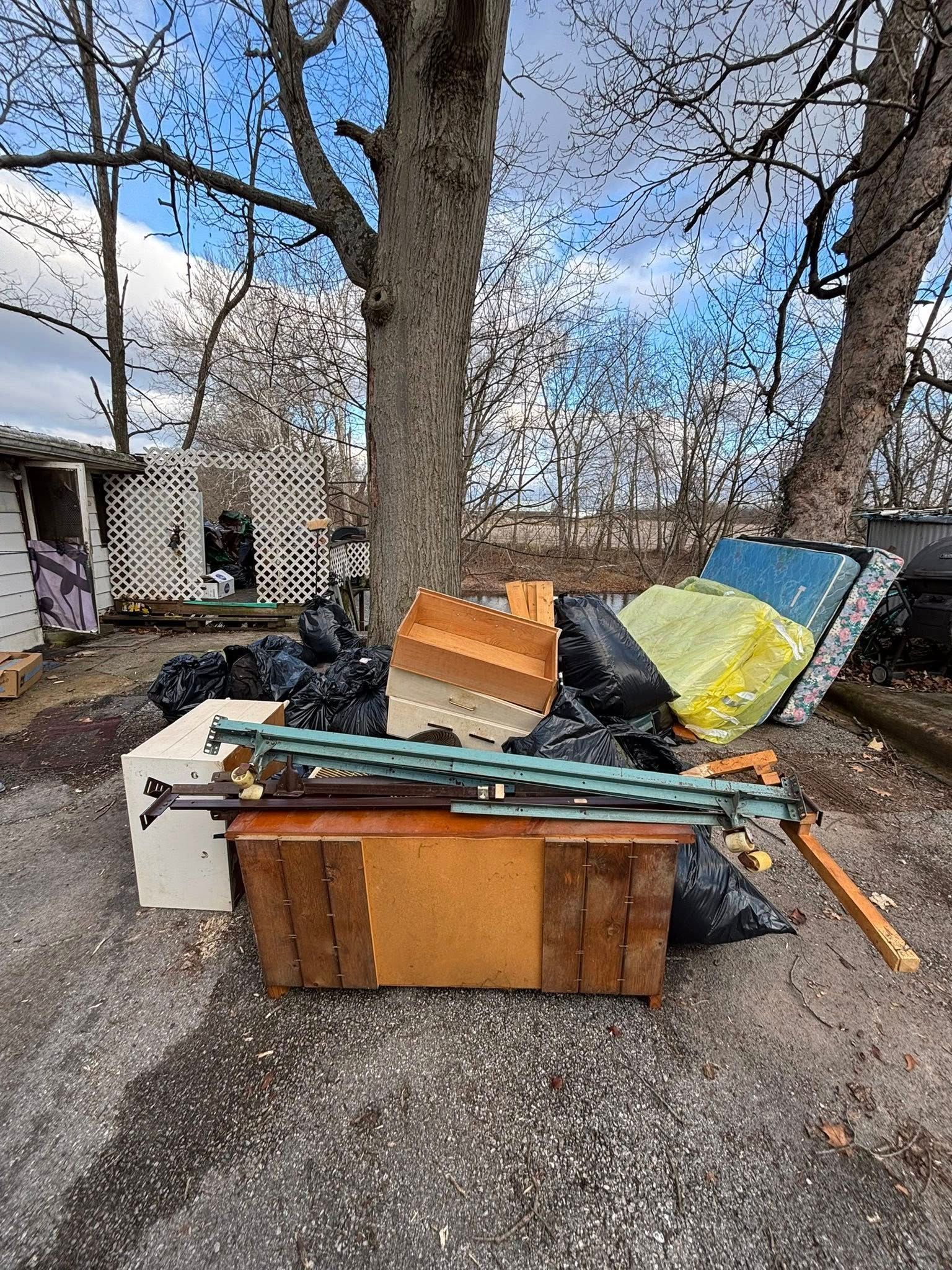 Woman in straw hat smiles, holding wine glass near a lake.