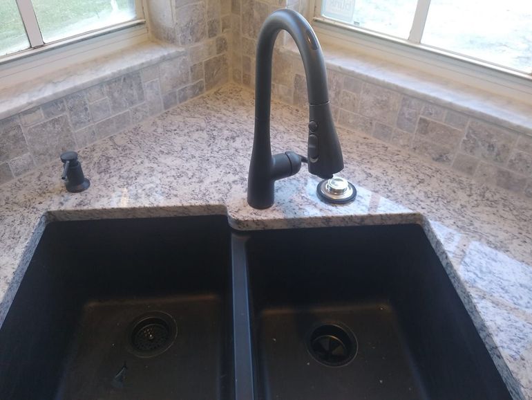 a kitchen sink with a black faucet and soap dispenser
