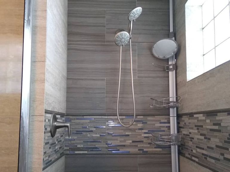 a shower with two shower heads and a mirror