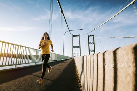 A young mixed race woman enjoys an early jog in the city of Tacoma, Washington. Her running takes her across the Tacoma Narrows bridge, with a running path spanning the Puget Sound from Tacoma to Gig Harbor.