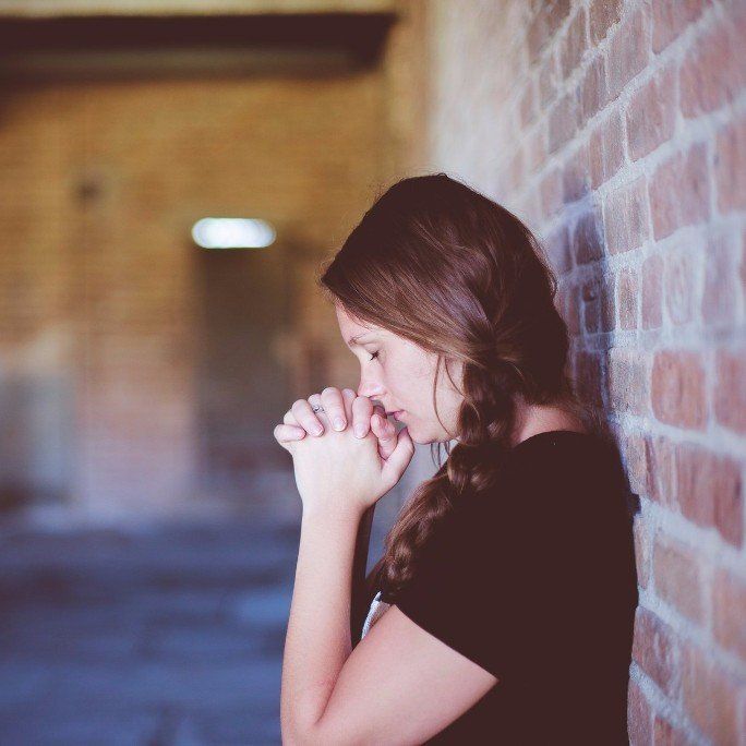 grieving woman praying - Philip J. Brendese Funeral Home