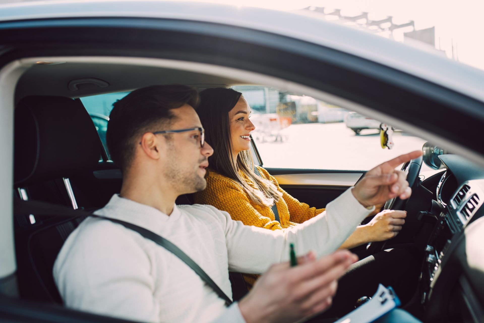 A woman is driving a car with her hands on the steering wheel.