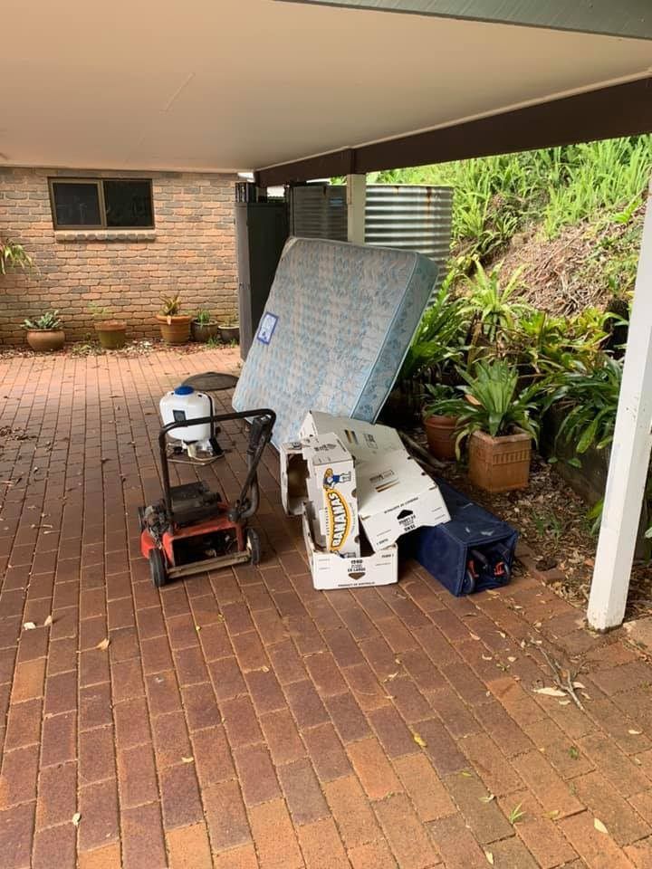A Mattress is Sitting on Top of a Brick Driveway Next to a Lawn Mower — A Load of Rubbish In Buderim, QLD