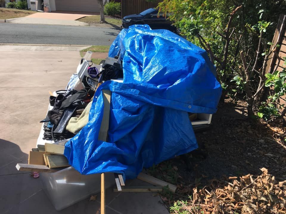 A Pile of Trash is Covered in a Blue Tarp — A Load of Rubbish In Buderim, QLD