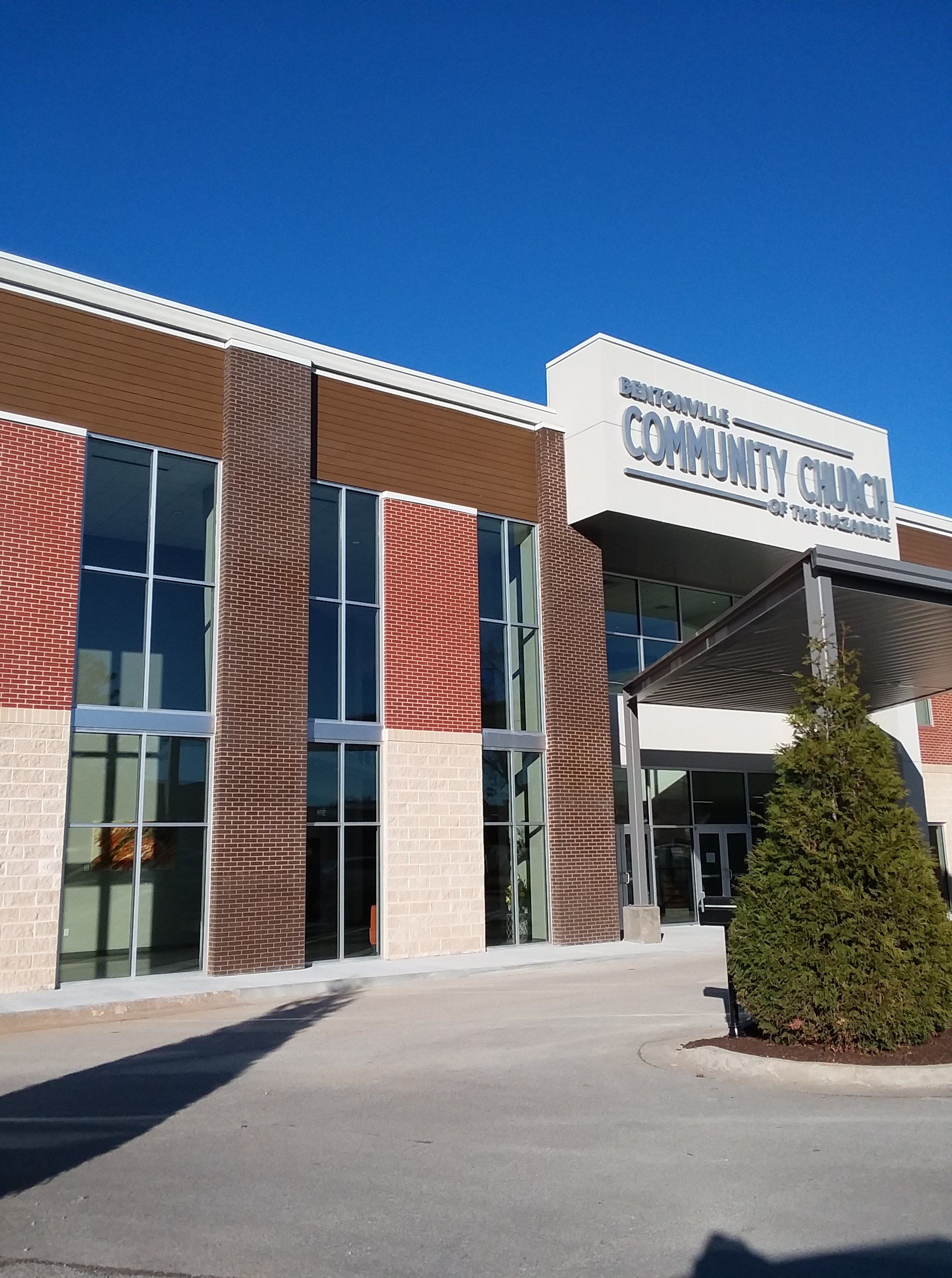 Modern Community Church exterior with tall windows, brick and patterned panels, clear blue sky.