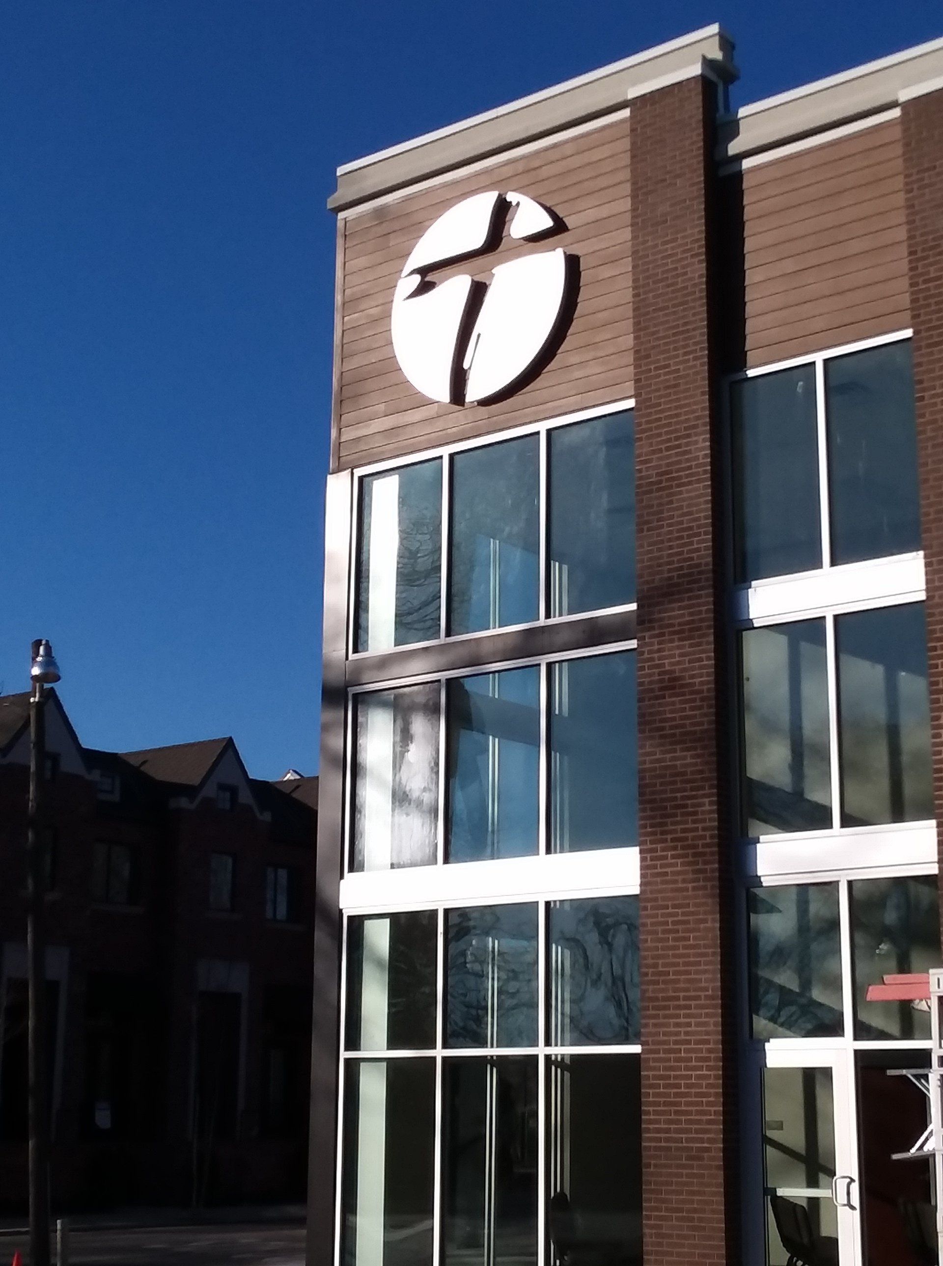 Modern brick building with large cross emblem. Blue sky background.