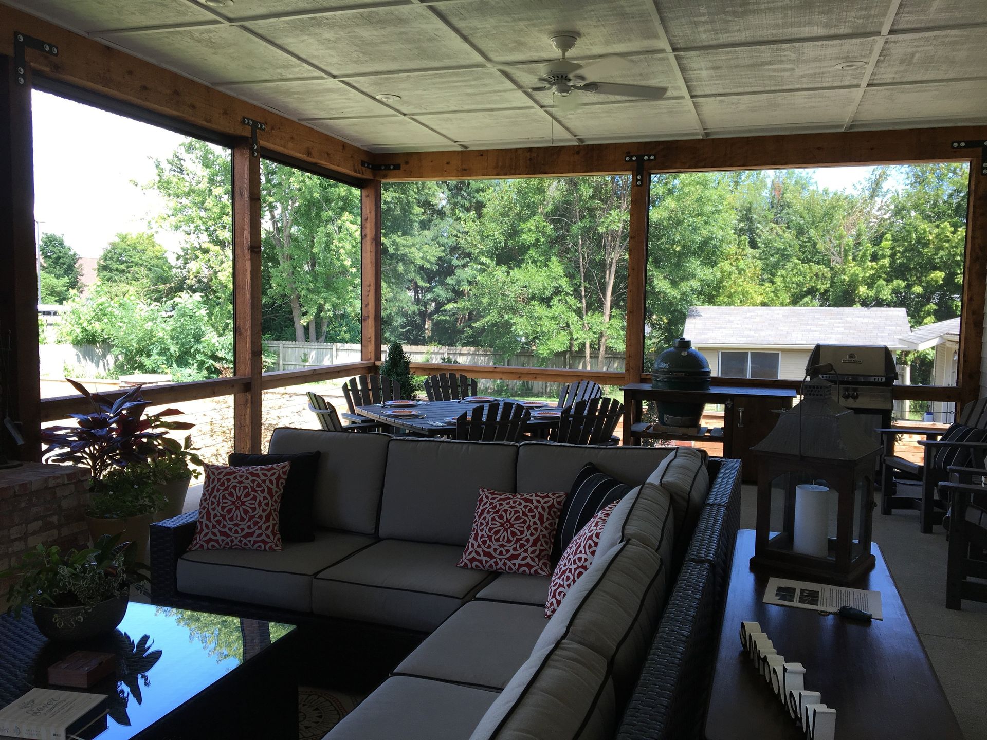 Screened-in porch with outdoor furniture; trees and a house are visible in the background.