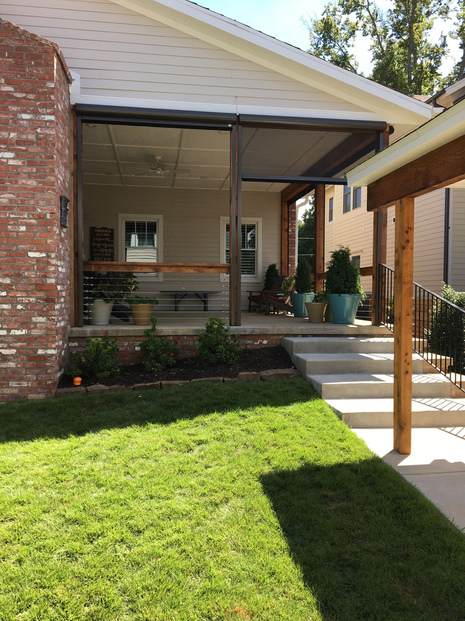 Porch with retractable screens, brick wall, steps, and potted plants.