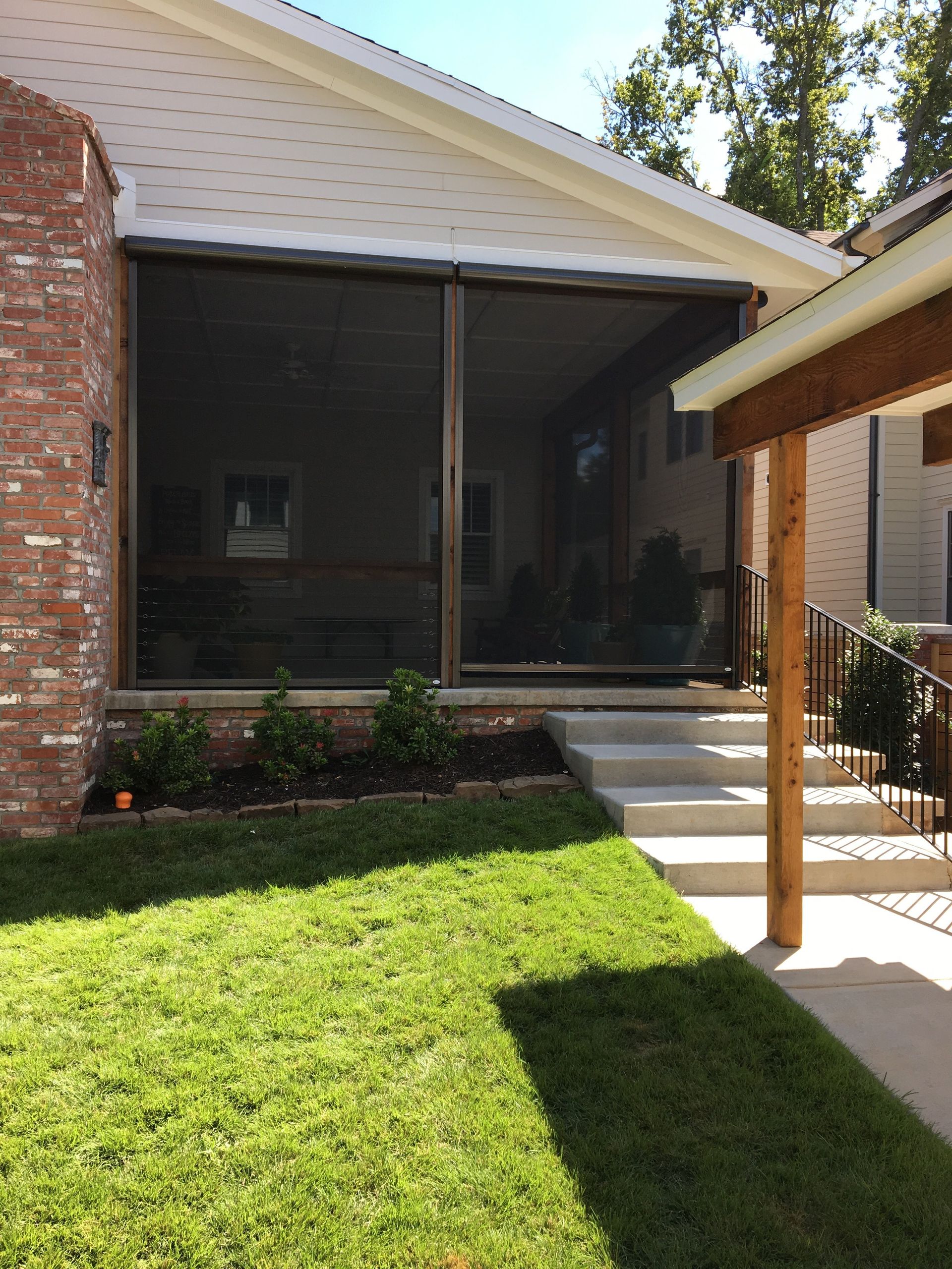 Screened porch with brown framing, white stairs, and green lawn.