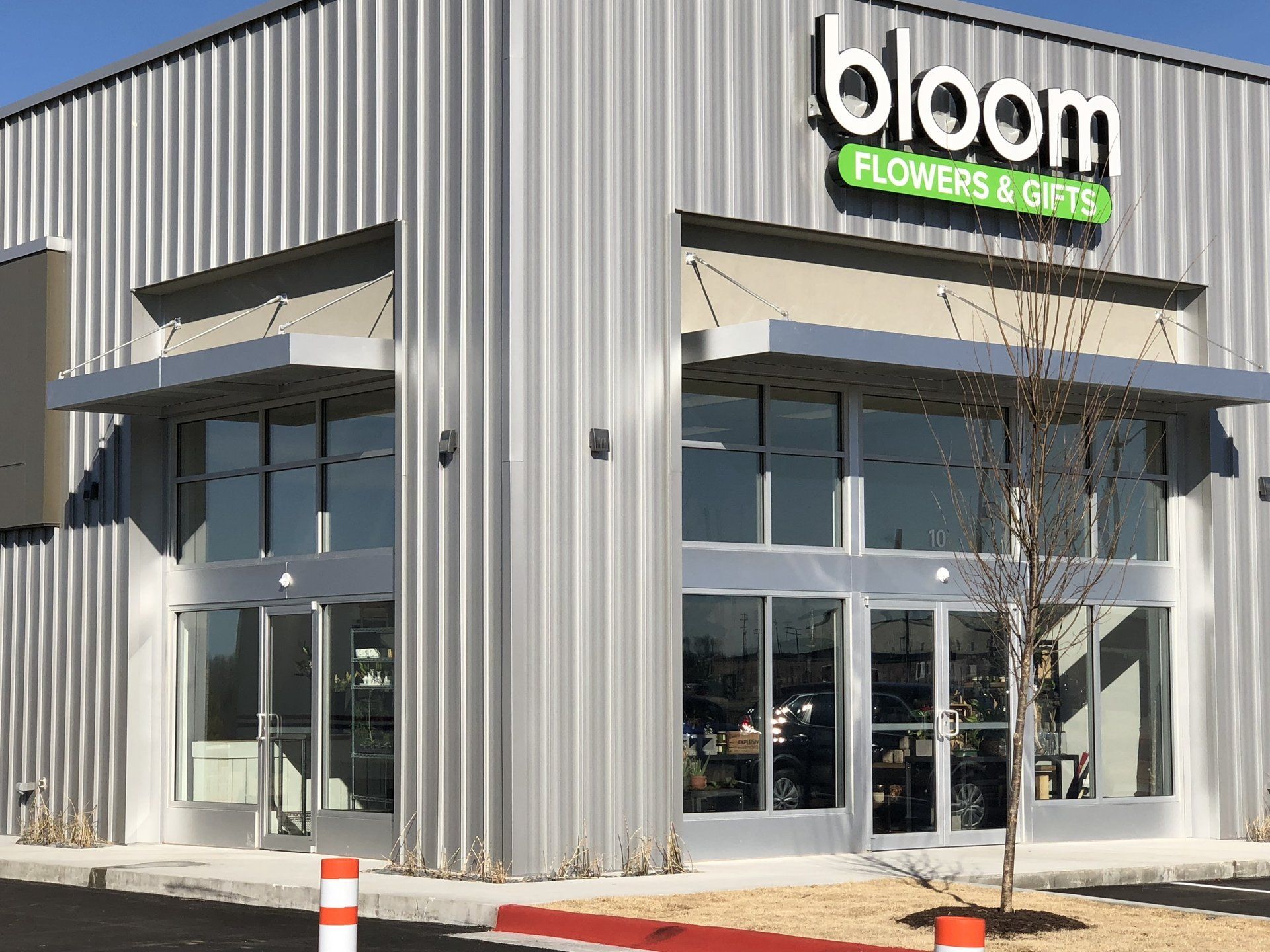 Bloom Flowers & Gifts storefront with a gray metal exterior, glass doors, and a green sign.