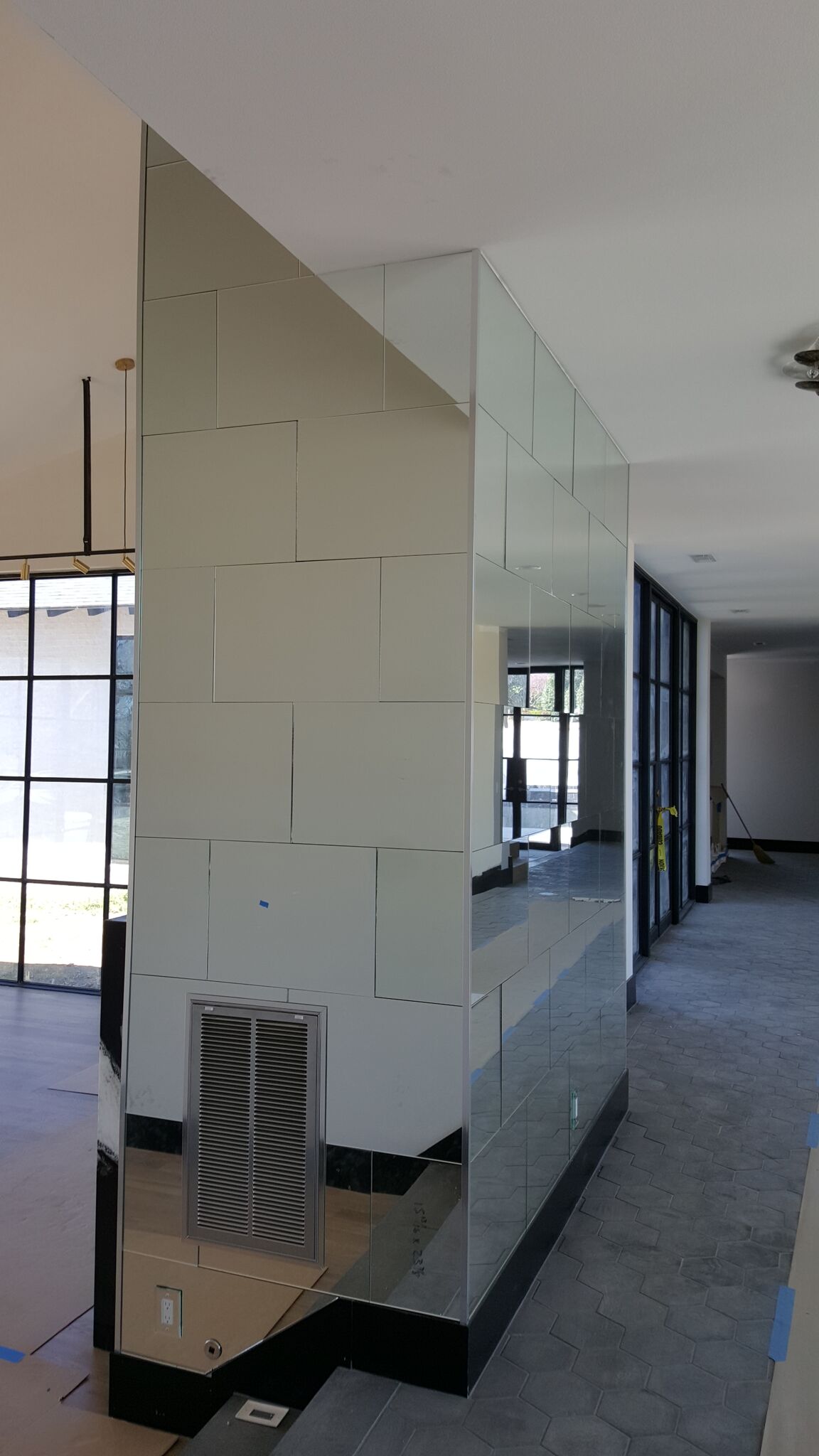 Mirrored pillar in a building interior reflecting windows, doors, and construction materials.