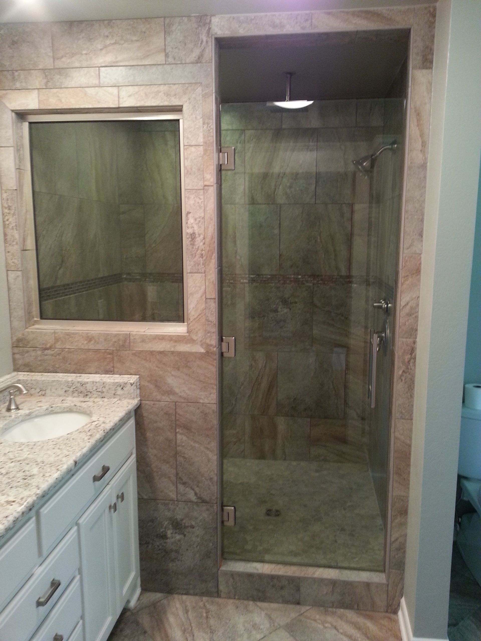 Bathroom with a walk-in shower, a vanity, and stone tiling on the walls.