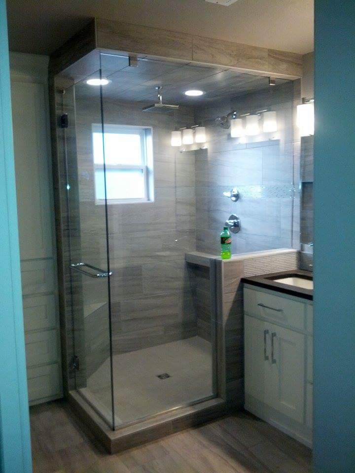 Glass shower with gray tile and white cabinets in a modern bathroom.