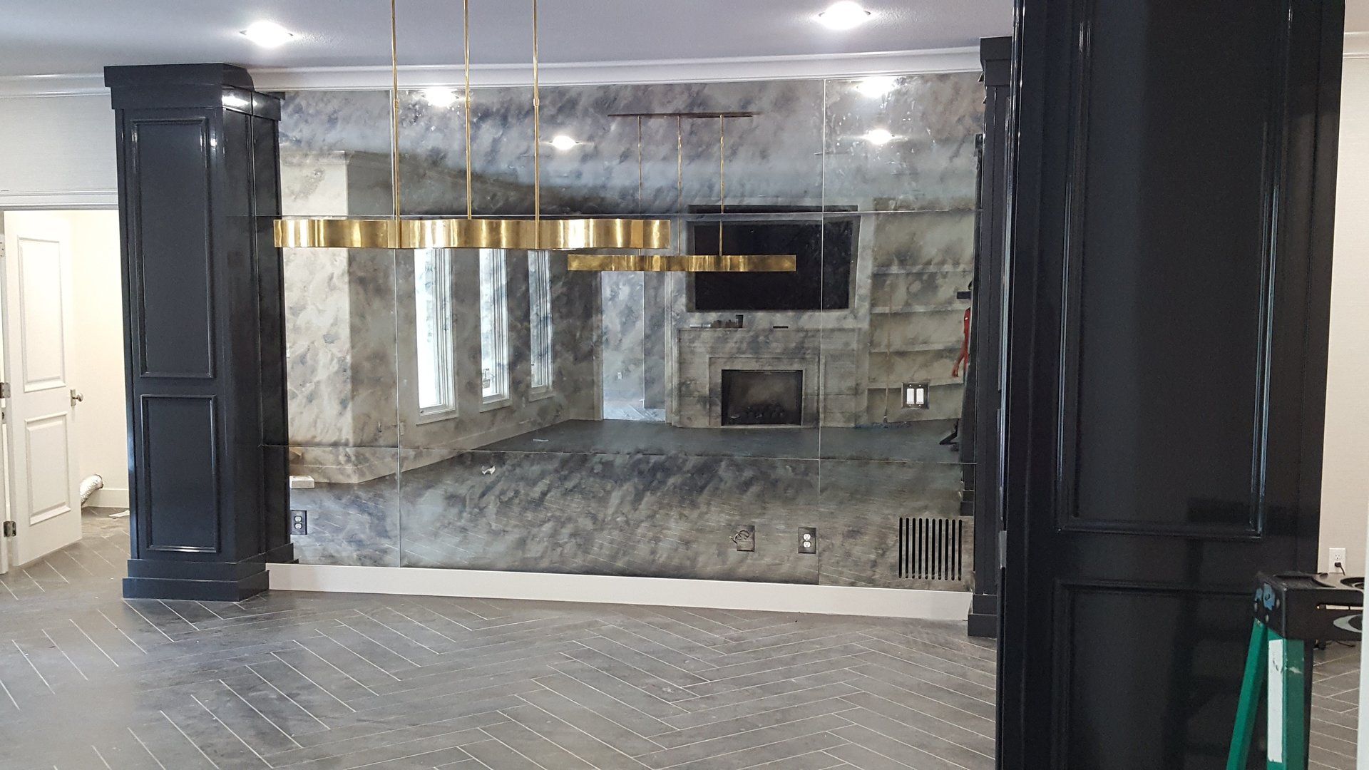 Room with stone wall, black columns, gold chandelier. Gray floor, white trim.