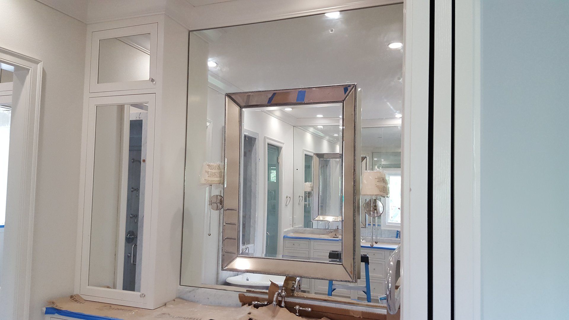 Bathroom with large mirrors, fixtures, and light blue walls reflecting the space.