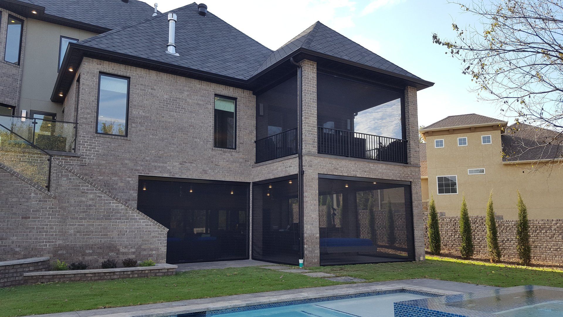 Brick house with screened-in patio overlooking a pool.
