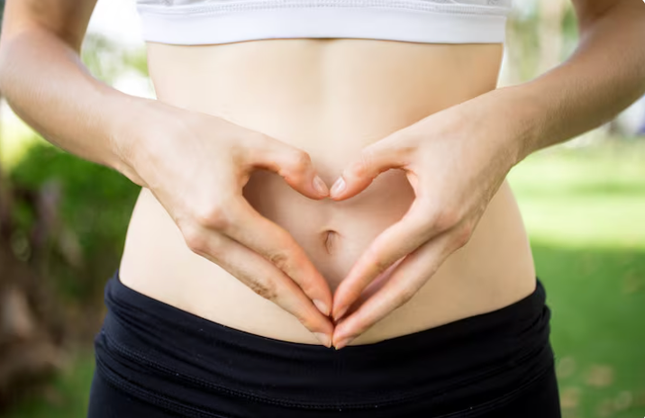 A lady holding a love heart hand signal over her stomach